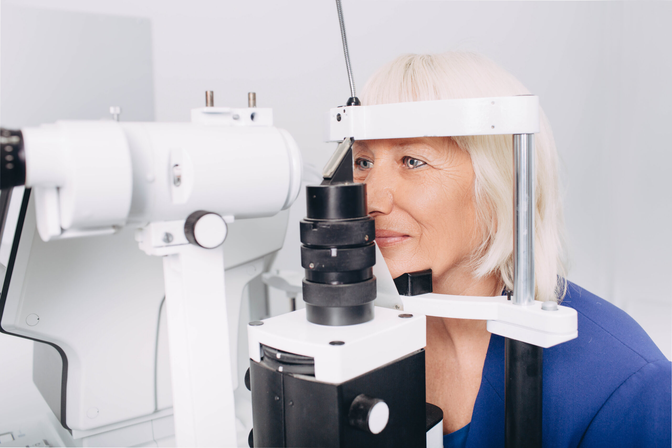 Senior woman receiving eye exam at clinic, eyesight examination old people